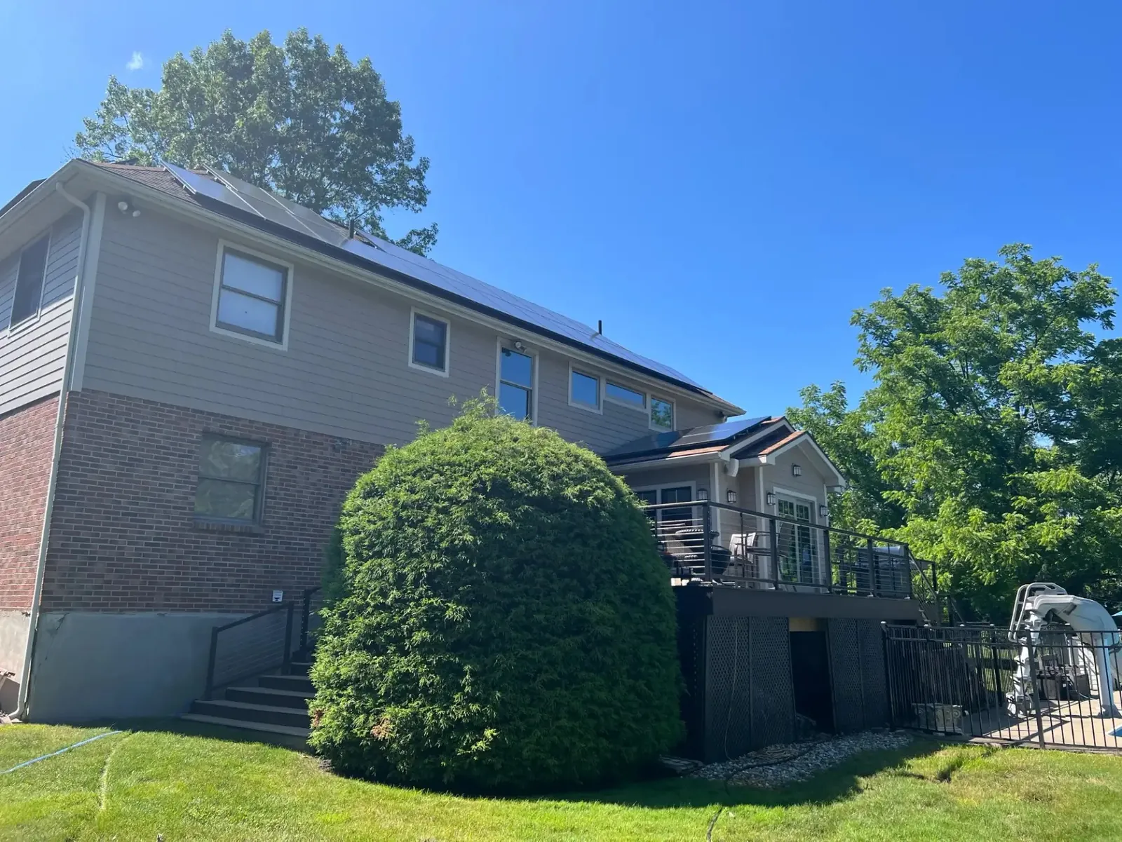 AEC customer home with rooftop solar panels, a rear deck, and a fenced pool