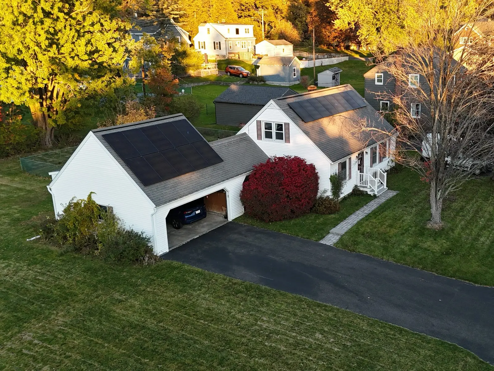 Rooftop solar panels on a white cape-style home and garage in Rensselaer, NY, installed by AEC Solar.